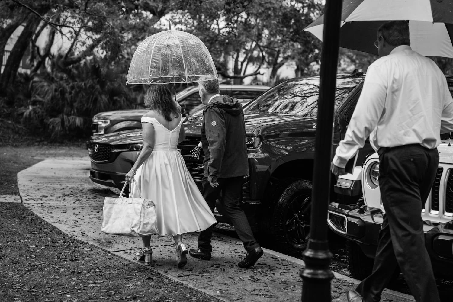 bride and groom walking in the rain with umbrella