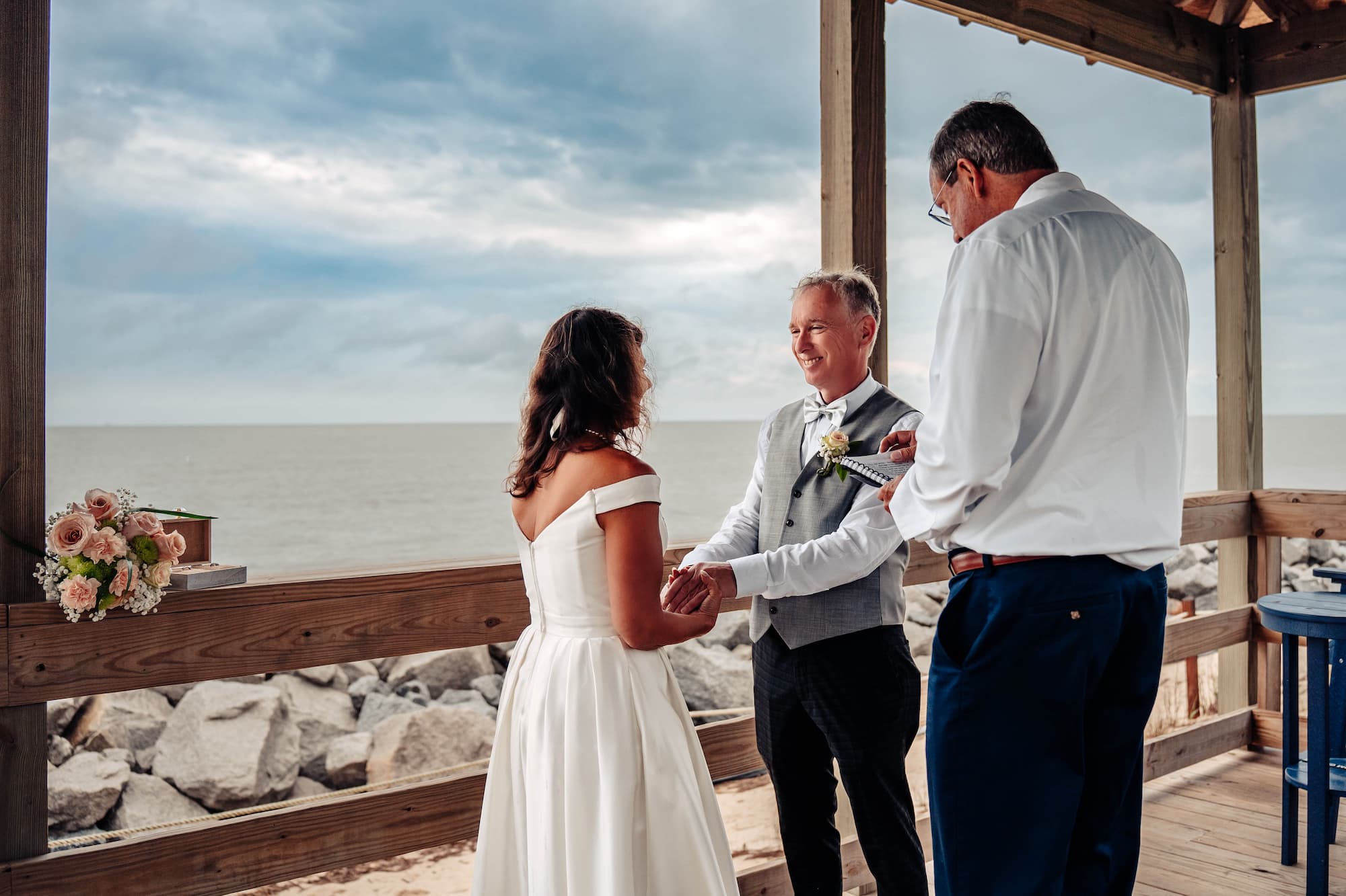 bride holding groom's hands at alter with wedding officiant